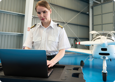 Pilot working on a laptop in a hangar